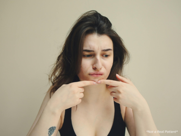 Woman checking face in mirror for breakouts and skin changes