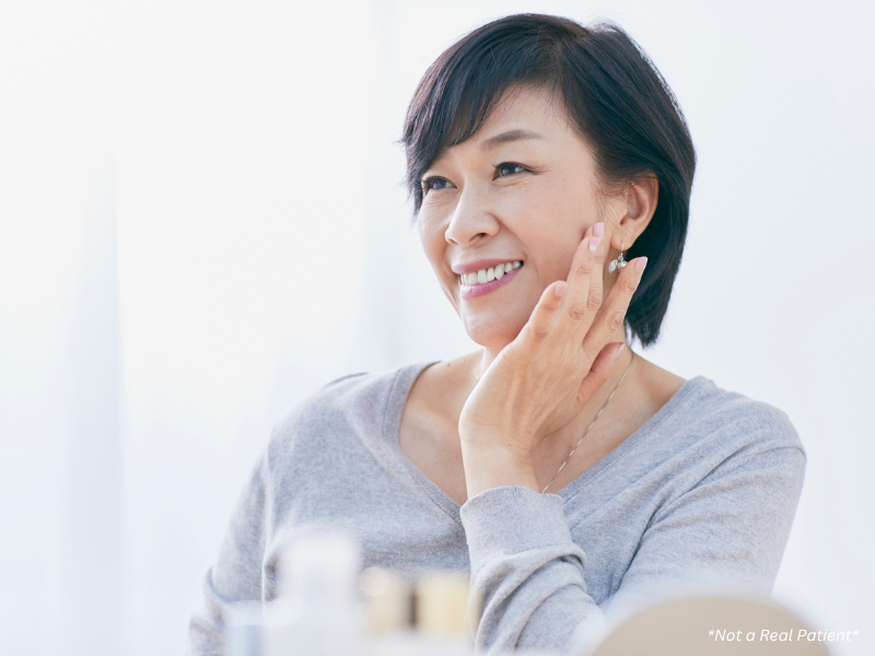“Woman applying skincare to support changing skin needs at different life stages”